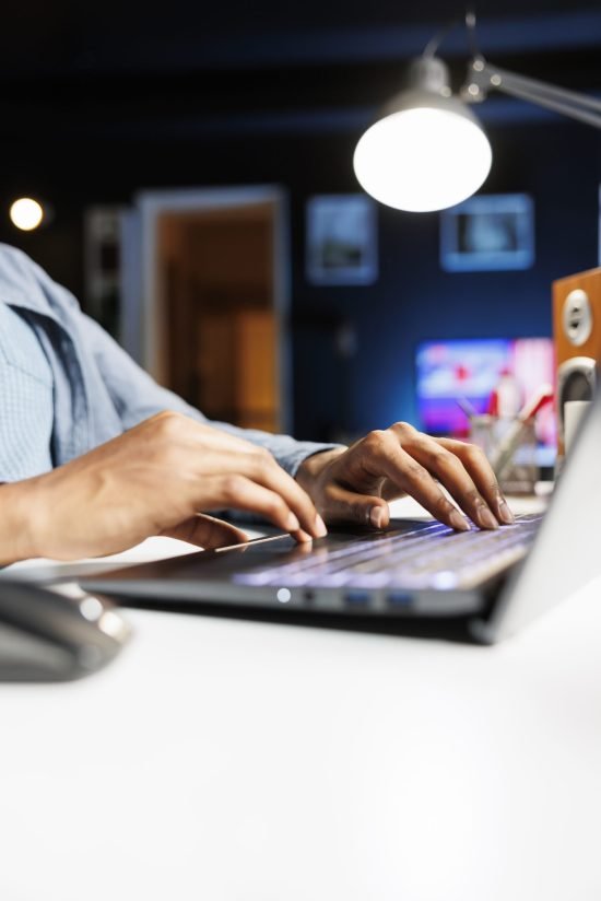 Remote tasks for company worker focusing on monthly earnings balance using legitimate financial details and web outputs. African american man manages his accounting tasks. Close up.